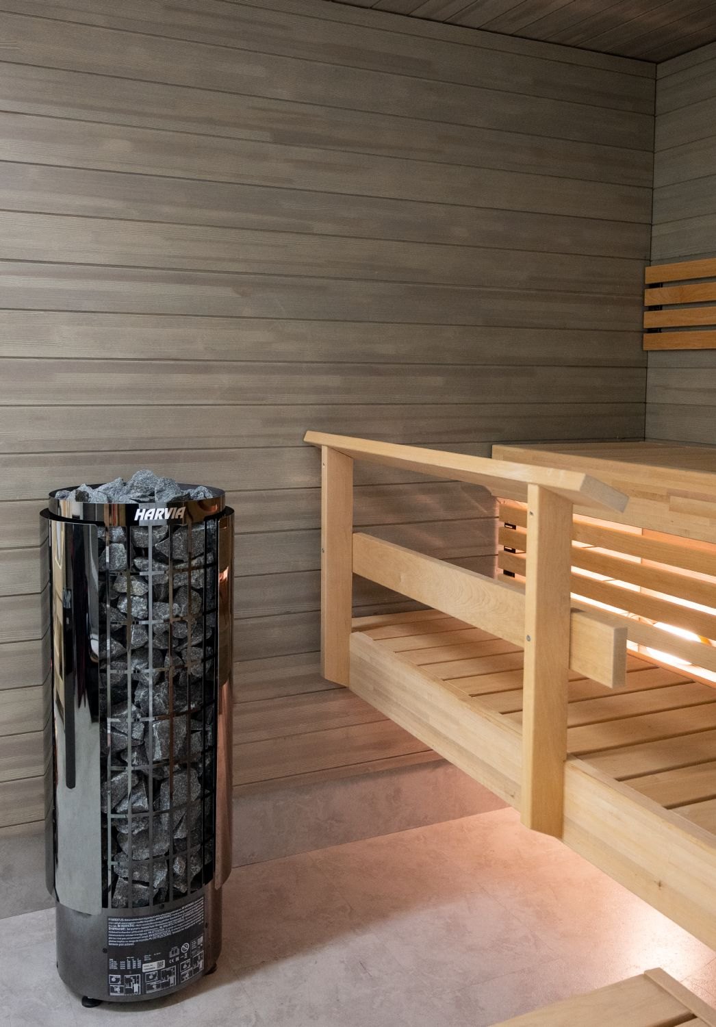 A Harvia Cilindro heater standing in a finished cedar sauna beside the benches